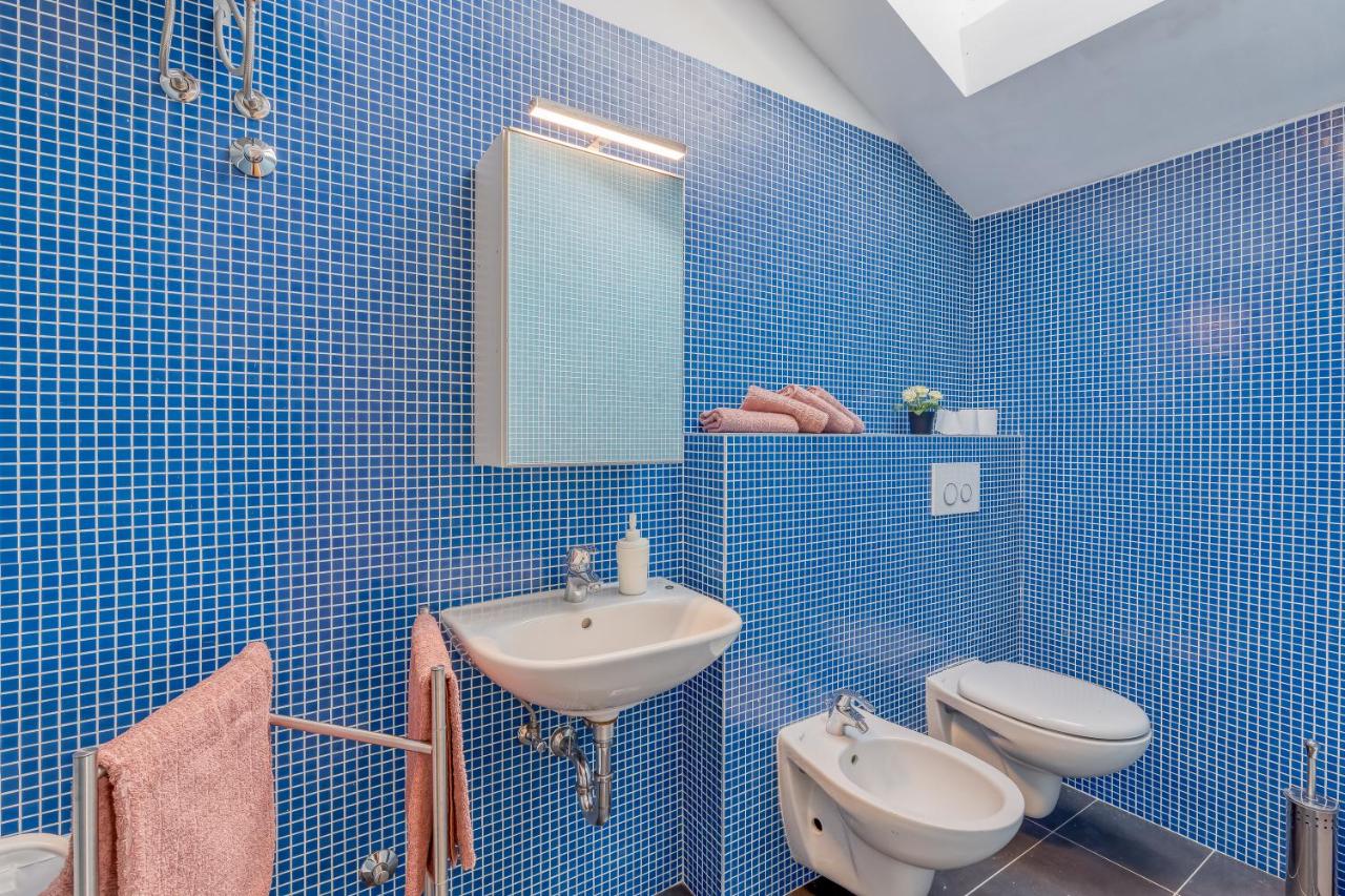 Blue-tiled bathroom with sink and toilet